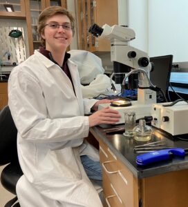 Outgoing Forest Health lab assistant Ethan Wachendorf at a microscope