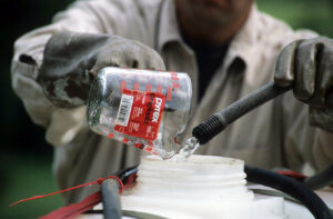 A worker rinses pesticide from a measuring cup