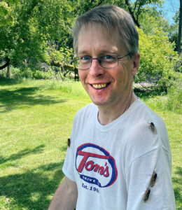 Photo showing a few periodical cicadas trying to hitch a ride on the T-shirt of Bill McNee, the Wisconsin Department of Natural Resources Forest Health specialist for northeast Wisconsin, in 2024 at Big Foot Beach State Park in Lake Geneva.