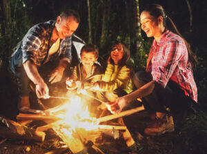 A stock photo of a family roasting marshmallows over a campfire.