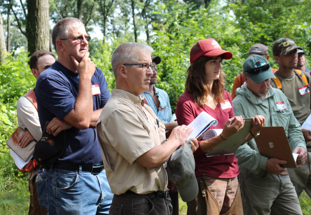 group of people listening to a speaker in the woods