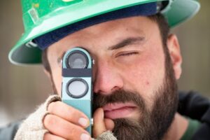 A worker inspects a tree with a pocket magnifier.